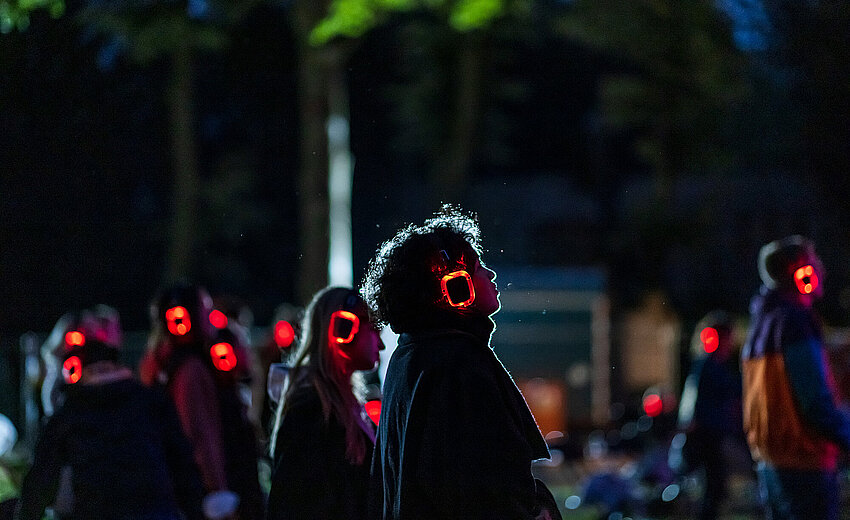 Menschen mit rot leuchtenden Kopfhörern auf einem Silent Concert im Spreepark